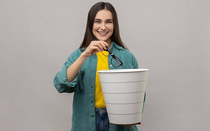 Woman putting glasses in trash can