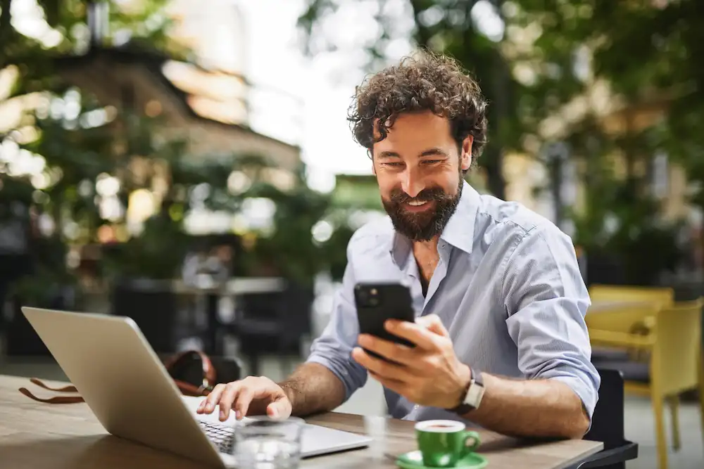 man looking at his phone and laptop